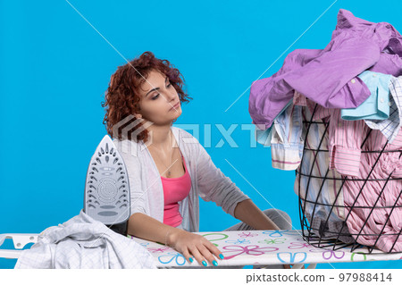 Girl saddened by the large amount of work to be done. Ironing clothes. 97988414