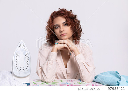 A girl worried about the next batch of shirts to be ironed. A girl worried about the next batch of shirts to be ironed. 97988421