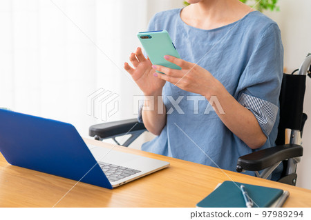 坐在輪椅上操作智能手機的年輕女性 多元社會的形象 坐在輪椅上操作智能手機的年輕女性 多元社會的形象 97989294