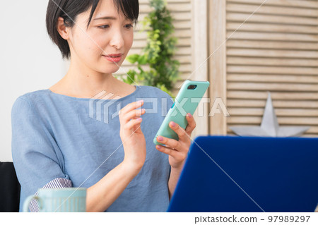 A young woman operating a smartphone while sitting in a wheelchair Image of a diverse society A young woman operating a smartphone while sitting in a wheelchair Image of a diverse society 97989297
