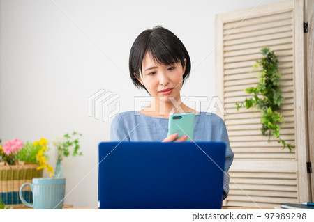 A young woman operating a smartphone while sitting in a wheelchair Image of a diverse society A young woman operating a smartphone while sitting in a wheelchair Image of a diverse society 97989298