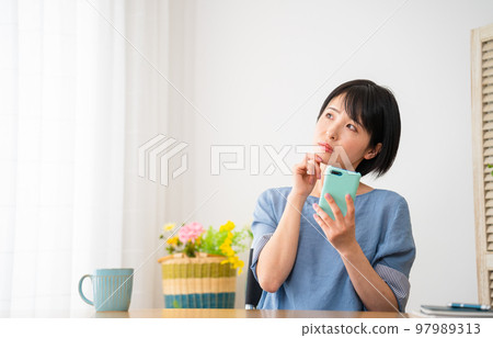 A young woman operating a smartphone while sitting in a wheelchair Image of a diverse society A young woman operating a smartphone while sitting in a wheelchair Image of a diverse society 97989313