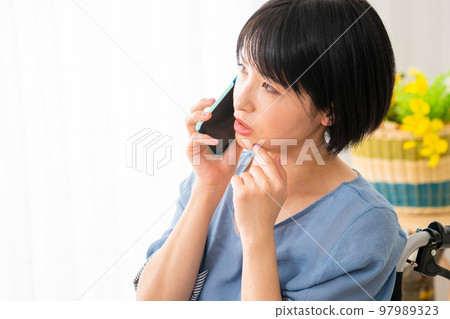 A young woman making a phone call while sitting in a wheelchair Image of a diverse society A young woman making a phone call while sitting in a wheelchair Image of a diverse society 97989323