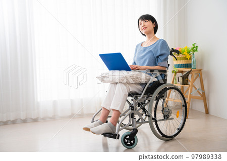 坐在輪椅上使用筆記本電腦的年輕女性 多元化社會的形象 坐在輪椅上使用筆記本電腦的年輕女性 多元化社會的形象 97989338