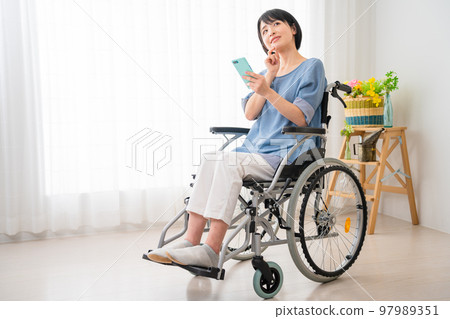 坐在輪椅上操作智能手機的年輕女性 多元社會的形象 坐在輪椅上操作智能手機的年輕女性 多元社會的形象 97989351