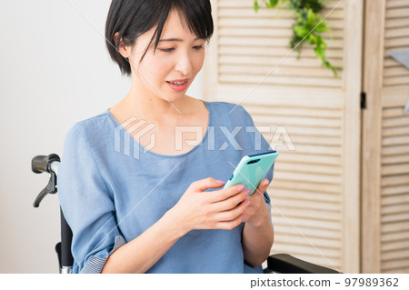 坐在輪椅上操作智能手機的年輕女性 多元社會的形象 坐在輪椅上操作智能手機的年輕女性 多元社會的形象 97989362