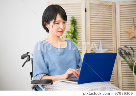 坐在輪椅上使用筆記本電腦的年輕女性 多元化社會的形象 坐在輪椅上使用筆記本電腦的年輕女性 多元化社會的形象 97989369