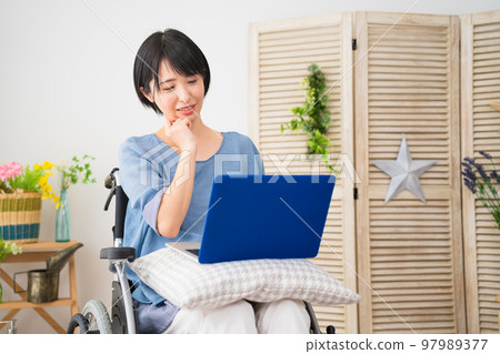 坐在輪椅上使用筆記本電腦的年輕女性 多元化社會的形象 坐在輪椅上使用筆記本電腦的年輕女性 多元化社會的形象 97989377