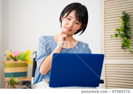 坐在輪椅上使用筆記本電腦的年輕女性 多元化社會的形象 坐在輪椅上使用筆記本電腦的年輕女性 多元化社會的形象 97989379