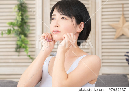 A young woman doing a self-massage of her chin Beauty image A young woman doing a self-massage of her chin Beauty image 97989387