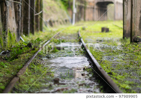 Close up of the railway track after the rain. Some green grass on the ground. Close up of the railway track after the rain. Some green grass on the ground. 97989905