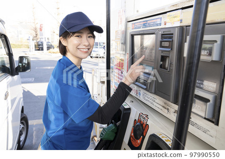 Woman refueling at a self-service gas station 97990550
