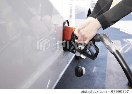 Hands of a woman refueling at a self-service gas station Hands of a woman refueling at a self-service gas station 97990597