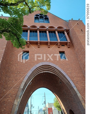 Telegraph poles and blue sky beyond the brick gate that looks like a face with a wide open mouth 97990639