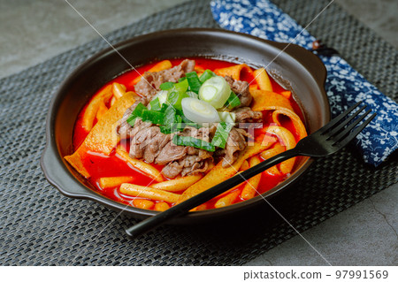 黑盤上放著辣味韓國菜 Tteokbokki,配有牛肉、蔬菜和魚餅 黑盤上放著辣味韓國菜 Tteokbokki,配有牛肉、蔬菜和魚餅 97991569