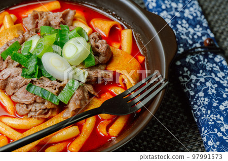 Spicy Korean food Tteokbokki with beef, vegetables and fish cake served on a black plate Spicy Korean food Tteokbokki with beef, vegetables and fish cake served on a black plate 97991573