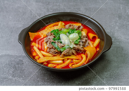 Spicy Korean food Tteokbokki with beef, vegetables and fish cake served on a black plate 97991588