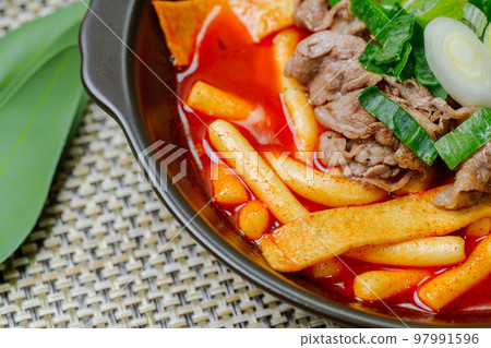 黑盤上放著辣味韓國菜 Tteokbokki，配有牛肉、蔬菜和魚餅 97991596