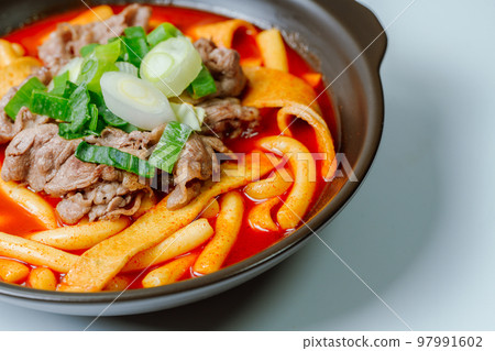 黑盤上放著辣味韓國菜 Tteokbokki，配有牛肉、蔬菜和魚餅 97991602