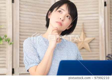 Young woman thinking in front of a laptop Young woman thinking in front of a laptop 97992210