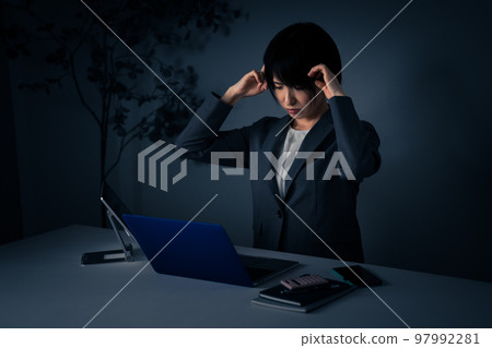 Young business woman holding her head in the office Overtime image Young business woman holding her head in the office Overtime image 97992281