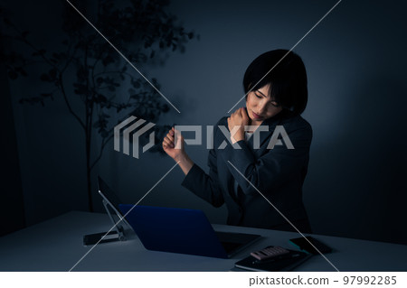 年輕的女商人在辦公室加班時揉著肩膀 年輕的女商人在辦公室加班時揉著肩膀 97992285