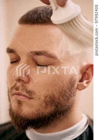 Barber shaving bearded man in barber shop 97992408
