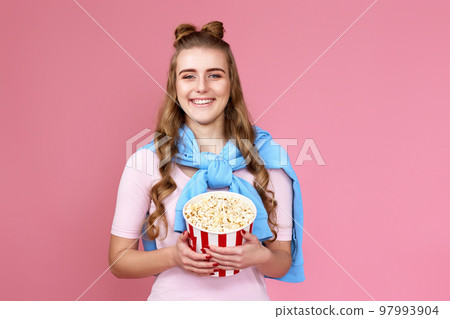 woman in sweatshirt watching movie film, eating popcorn woman in sweatshirt watching movie film, eating popcorn 97993904