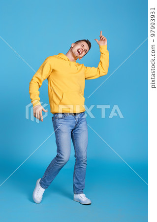 happy young man dancing on blue background. 97993931