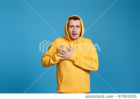 young man in yellow sweatshirt with hands on chest 97993936