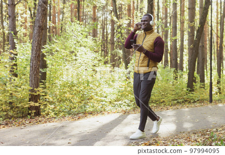 African american man listens music in spring park copy space and place for advertising. Gadget, app and streaming service concept 97994095