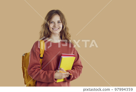 Portrait of happy smiling student girl with backpack and folders on beige background. 97994359