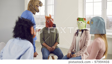 Team of people wearing monkey, horse, dinosaur, frog and pigeon masks having a meeting 97994408