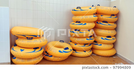Stacks of yellow water tubes, lying near a light tiled wall Stacks of yellow water tubes, lying near a light tiled wall 97994809