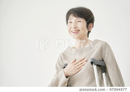 Portrait of a smiling middle-aged woman using crutches White background 97994977
