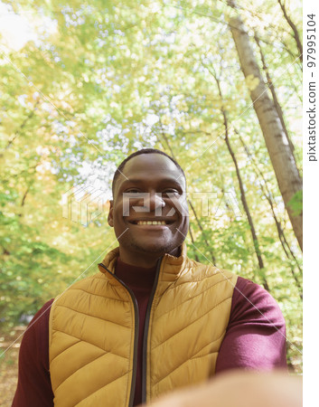 African American man taking a self portrait with a smartphone in autumn fall or video call portrait. Happy people, season and videocall concept 97995104