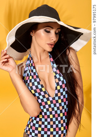 Young sexy confident brunette woman posing before camera, wearing bikini and big nice black hat Young sexy confident brunette woman posing before camera, wearing bikini and big nice black hat 97995175