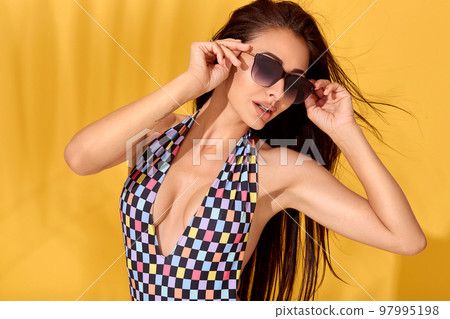 Close up Image of beautiful young sexy slim brunette woman posing on yellow background. Swimsuit swimwear or bikini model 97995198