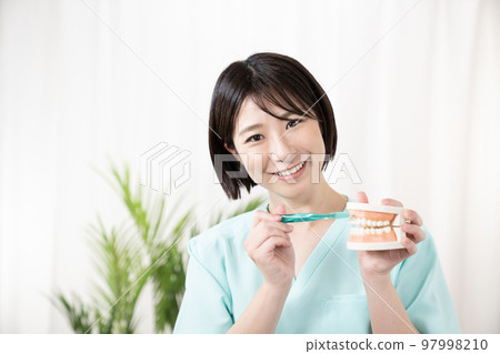 Dental hygienist with tooth model and toothbrush 97998210