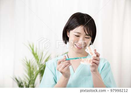 Dental hygienist with tooth model and toothbrush Dental hygienist with tooth model and toothbrush 97998212