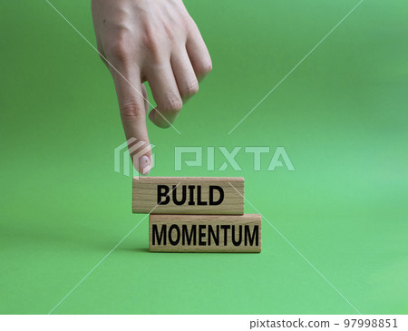 Build momentum symbol. Wooden blocks with words Build momentum. Beautiful green background. Businessman hand. Business and Build momentum concept. Copy space. 97998851