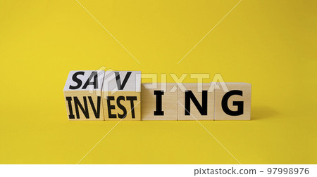 Saving and Investing symbol. Turned wooden cubes with words Investing and Saving. Beautiful yellow background. Business and Saving and Investing concept. Copy space Saving and Investing symbol. Turned wooden cubes with words Investing and Saving. Beautiful yellow background. Business and Saving and Investing concept. Copy space 97998976