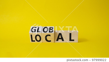 Global and Local symbol. Turned wooden cubes with words Global and Local. Beautiful yellow background. Business and Global and Local concept. Copy space 97999022