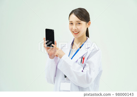 A woman in a white coat showing a smartphone screen 98000143
