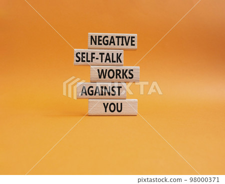 Negative self-talk works against you symbol. Concept words Negative self-talk works against you on wooden blocks. Beautiful orange background. Psychological concept. Copy space 98000371