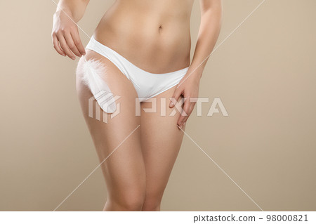 Woman with feather showing smooth skin on beige background, closeup. Brazilian bikini epilation Woman with feather showing smooth skin on beige background, closeup. Brazilian bikini epilation 98000821