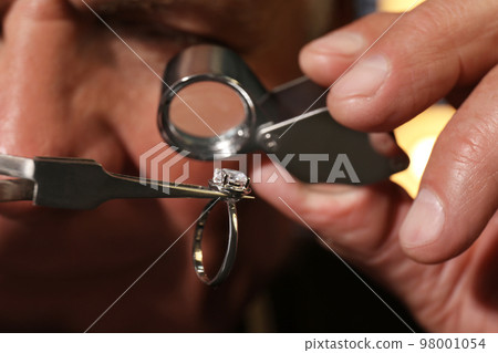 Professional jeweler evaluating beautiful ring, closeup view 98001054