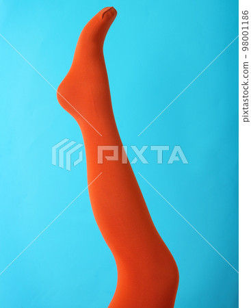Leg mannequin in orange tights on blue background 98001186