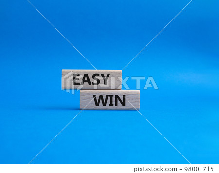 Easy win symbol. Wooden blocks with words 'Easy win'. Beautiful blue background. Business and 'Easy win' concept. Copy space. Easy win symbol. Wooden blocks with words 'Easy win'. Beautiful blue background. Business and 'Easy win' concept. Copy space. 98001715
