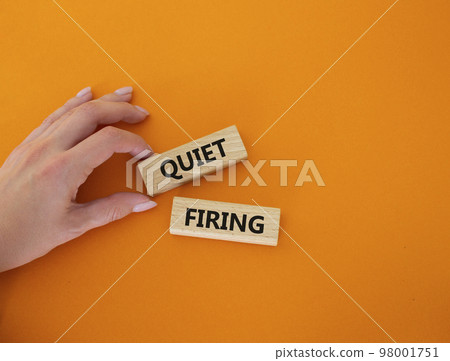 Quiet firing symbol. Concept word Quiet firing on wooden blocks. Businessman hand. Beautiful orange background. Business and Quiet firing concept. Copy space Quiet firing symbol. Concept word Quiet firing on wooden blocks. Businessman hand. Beautiful orange background. Business and Quiet firing concept. Copy space 98001751